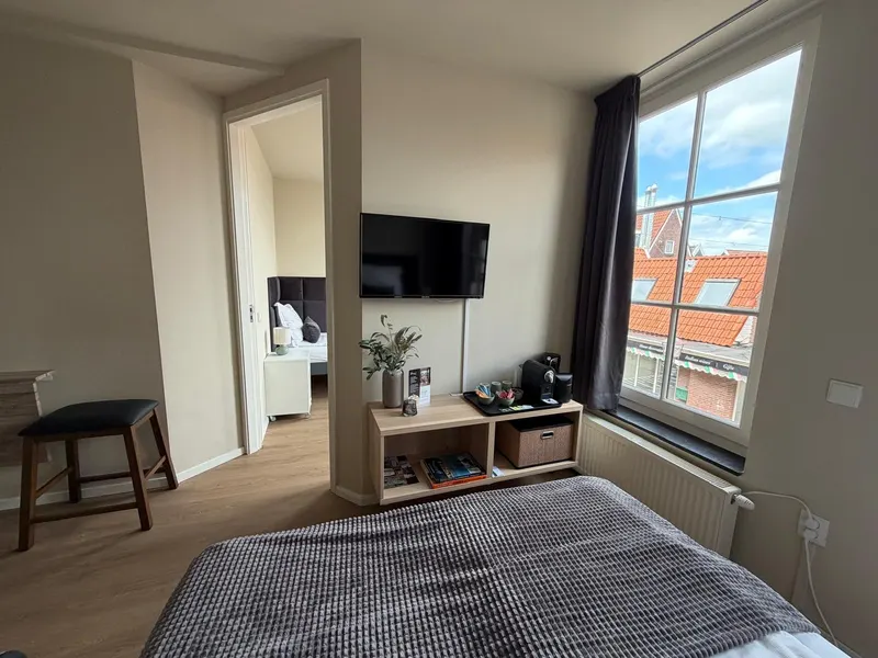 Driepersoonskamer met tv, koffiehoek en groot raam bij Harbour Stay Volendam op nummer 13a